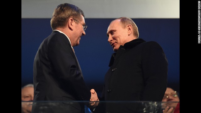 Thomas Bach, president of the International Olympic Committee, shakes hands with Russian President Vladimir Putin, right.
