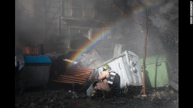 A rainbow forms over a protester ducking for cover in Kiev on February 18.
