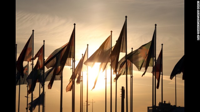 Before the start of the ceremony, the sun sets behind delegation flags.