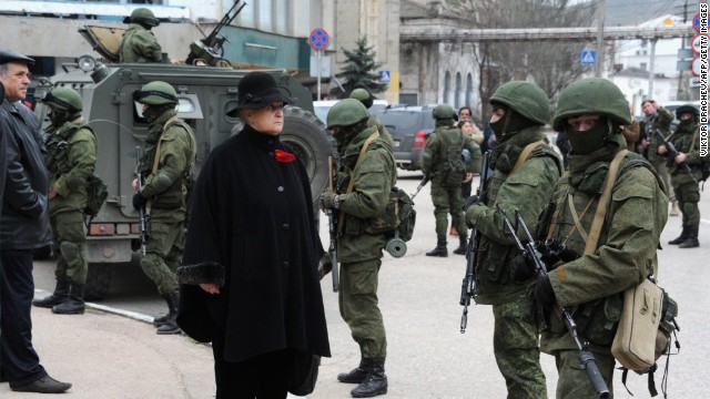 A woman waits in front of unidentified men in military fatigues blocking a base of the Ukrainian frontier guard unit in Balaklava, Ukraine, on March 1.