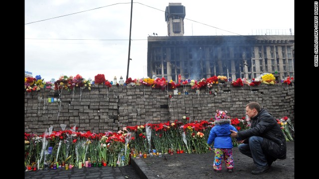 A man and his daughter lay flowers at a memorial for protesters killed in Independence Square. 