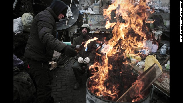 A man adds fuel to a fire at a barricade in Independence Square on February 27. Dozens of people were killed last week during clashes between security forces and protesters.