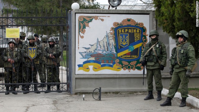 Ukrainian soldiers, left, and unidentified gunmen, right, stand at the gate of an infantry base in Perevalnoye, Ukraine, on March 2. 
