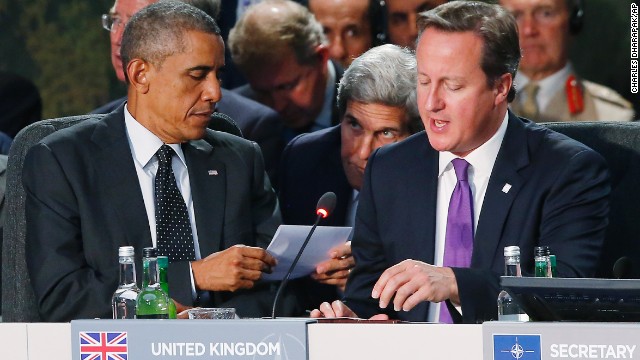 U.S. Secretary of State John Kerry passes a note to Obama as British Prime Minister David Cameron speaks during a NATO meeting on September 4.