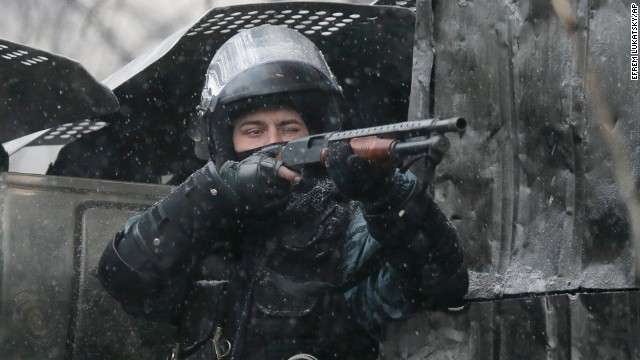 A police officer aims his shotgun during clashes with protesters.